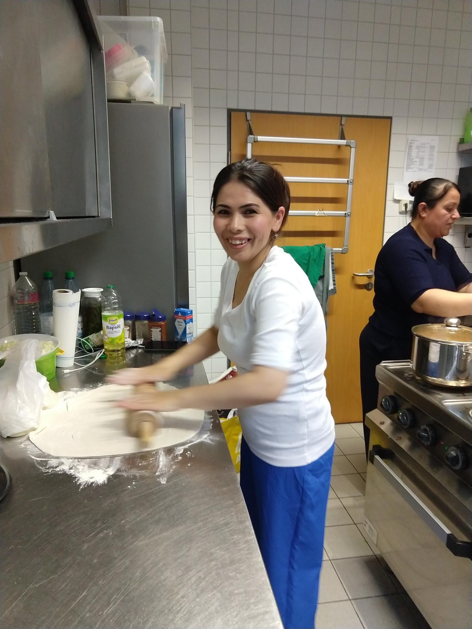 Auf einem Buffet stehen große Teller mit unterschiedlichen Speisen auf einer roten und gelben Tischdecke.