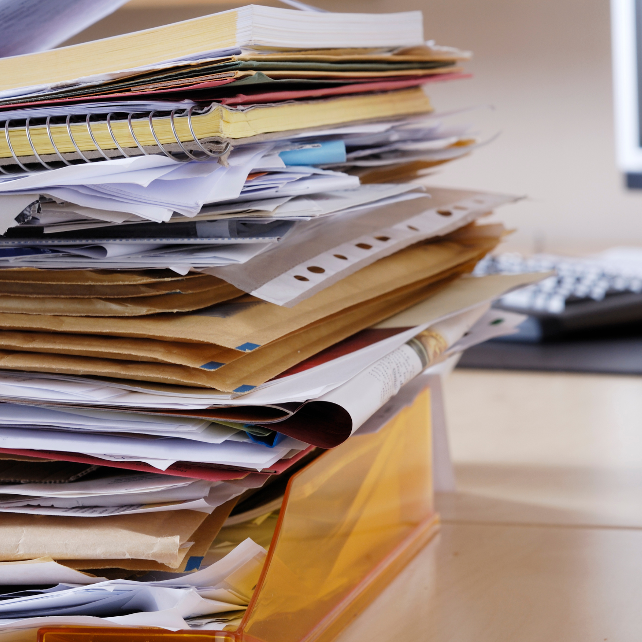 Ein hoher Stapel Papiere und Briefe liegt in einer Box auf einem Schreibtisch.