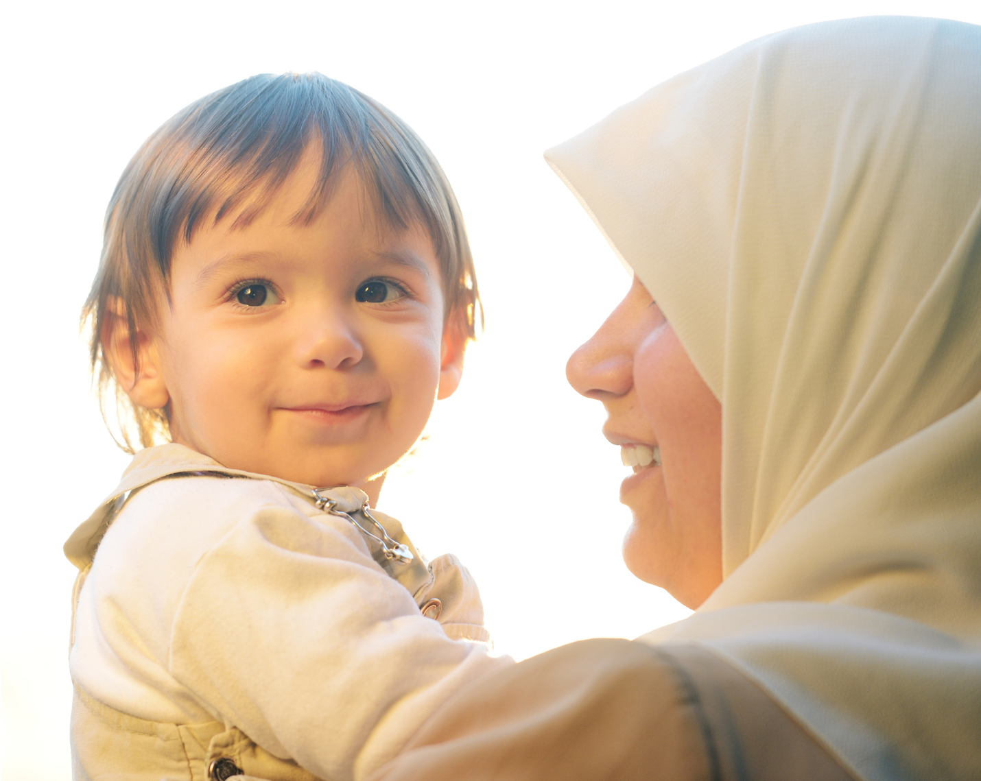Eine Frau hält ein Kleinkind auf dem Arm. Das Kind schaut gut gelaunt in die Kamera, die Frau ist von der Seite zu sehen. Sie lächelt das Kind an. Der Link führt zu den Angeboten unter sechs Jahren.