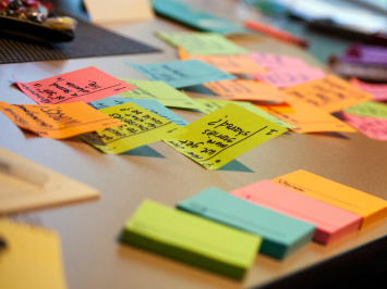 Viele bunte Klebezettel mit Notizen sind zu sehen. Der Link führt zu mehr Informartionen zu Sprach-Projekten.