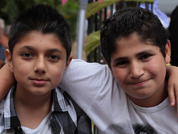 Zwei Freunde legen die Arme um die Schultern des anderen. Die Jungen sind ungefähr 12 Jahre alt.